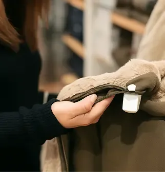 A person's hand holds up a beige garment with a white tag, inspecting the fabric.