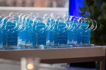 Row of blue translucent awards displayed on a table for a ceremony.