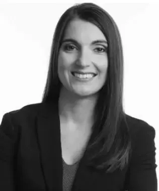 Black and white headshot of a smiling woman with dark hair in a blazer.