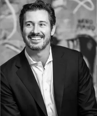 Black and white portrait of a smiling man with a beard and dark hair.
