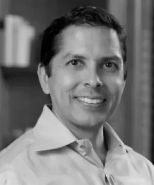 Black and white headshot of a smiling man with short dark hair in a collared shirt.