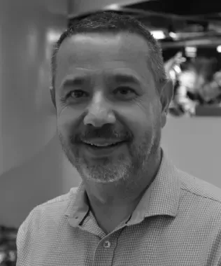 Black and white portrait of a smiling man with short hair and a polo shirt.
