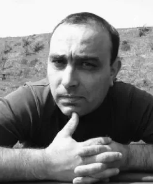 Black and white portrait of a man with clasped hands, deep in thought.