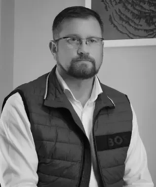 Black and white portrait of a man with glasses and a beard in a vest.