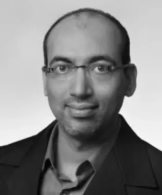 Black and white headshot of a smiling man with glasses.