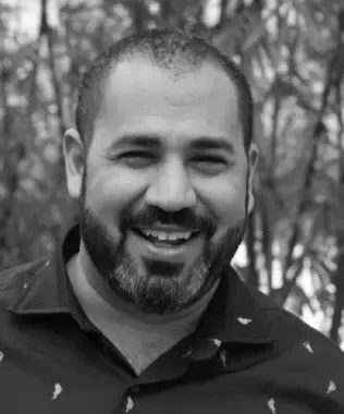 Black and white headshot of a smiling man with short dark hair.