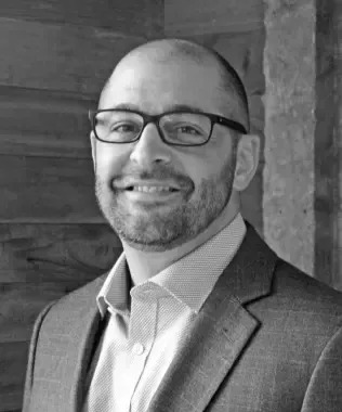 Black and white headshot of a smiling man with Asian features.