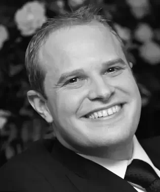 Black and white portrait of a man with glasses and a beard.