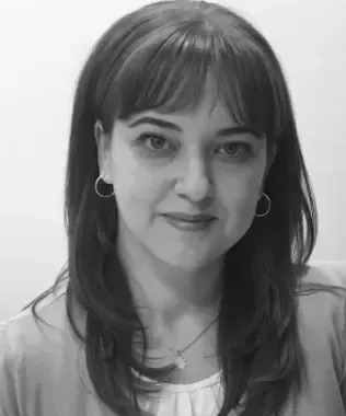 Black and white portrait of a smiling man with shaved sides and a beard.
