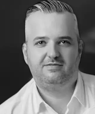 Black and white portrait of a man with a dark jacket outdoors.
