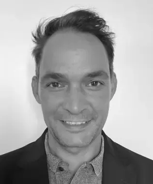 Black and white portrait of a smiling man in a suit jacket.