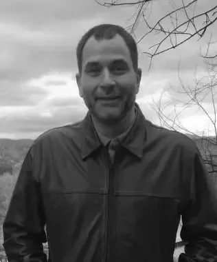 Black and white portrait of a man with dark hair and a white shirt.