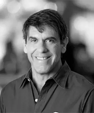 Black and white headshot of a smiling man with short dark hair, wearing a collared shirt.
