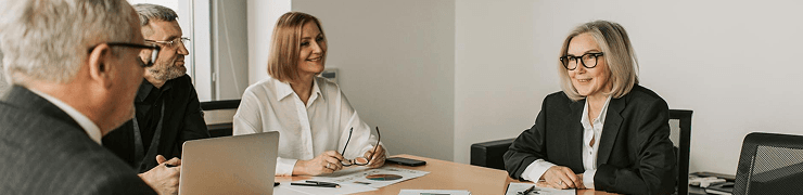 Diverse business professionals gather around a table, engaged in a collaborative meeting.