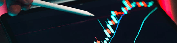 A white stylus interacts with a digital screen displaying a financial candlestick chart.