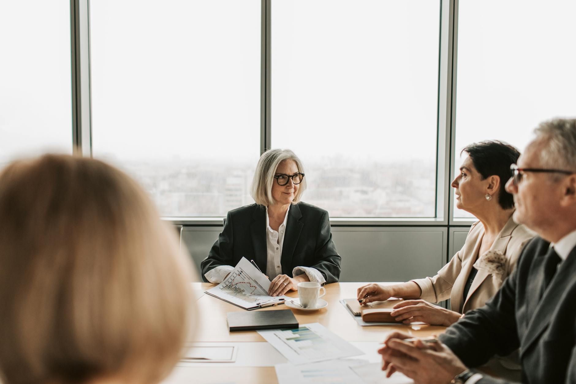 A diverse group of business professionals collaborates around a conference table in a modern office.