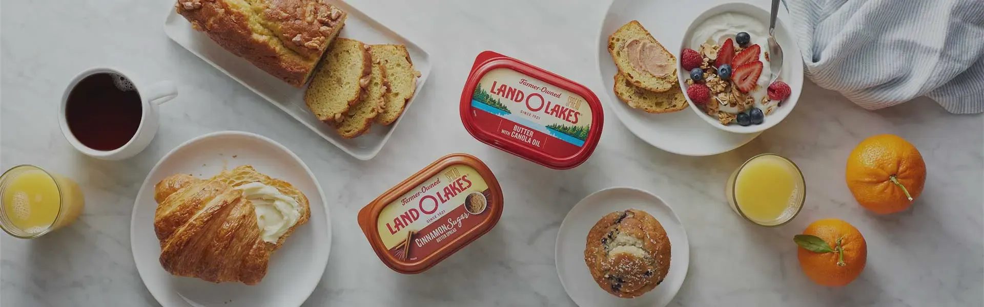 A breakfast spread with pastries, coffee, juice, fruit yogurt, and Land O'Lakes products.