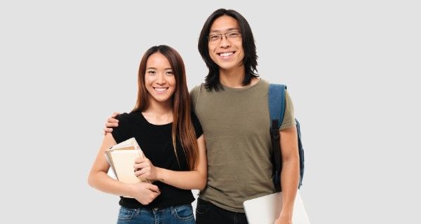 Two smiling Asian students, a woman holding books and a man with a laptop and backpack.