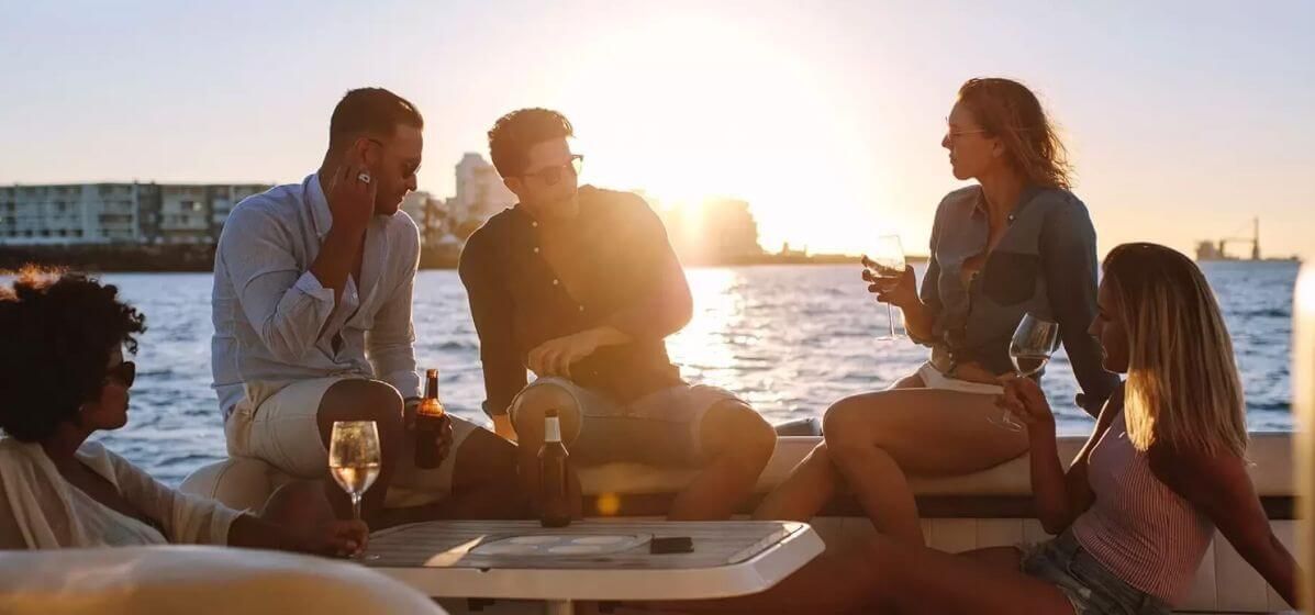 Friends relaxing on a boat at sunset, enjoying drinks and conversation on the water.