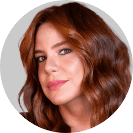 Headshot of a woman with auburn hair, looking right and smiling subtly.