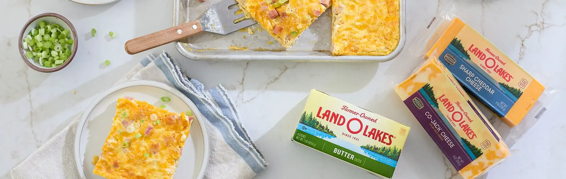 Golden breakfast casserole with Land O'Lakes butter and cheese products on a marble surface.