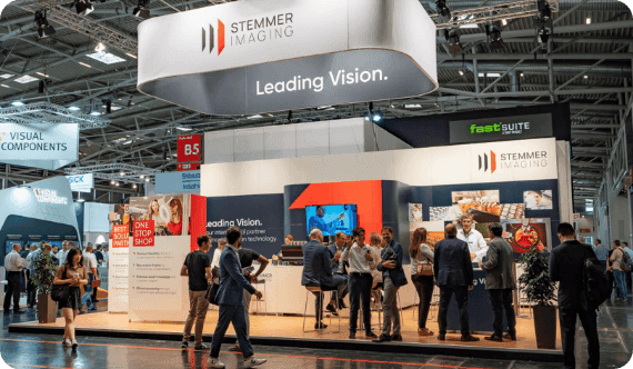 People gather and network at the busy STEMMER IMAGING booth with 'Leading Vision' signage.
