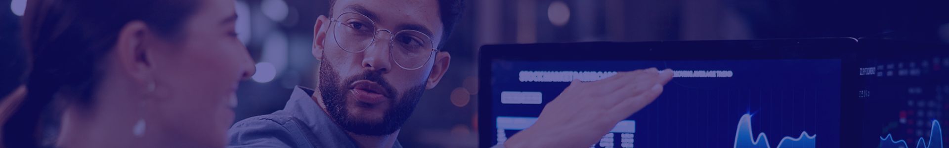 Two colleagues intently review data displayed on a monitor, collaborating in a professional setting.