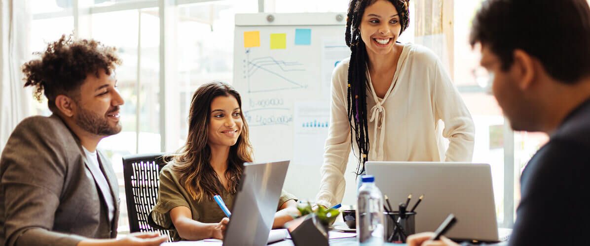 Three diverse professionals collaborating and smiling during a business meeting in a modern office.