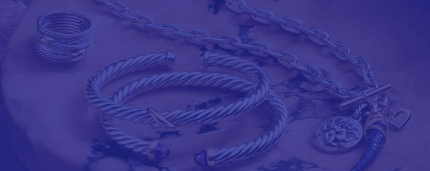 Silver ring, twisted bracelets, and chains arranged on a surface with a blue overlay.